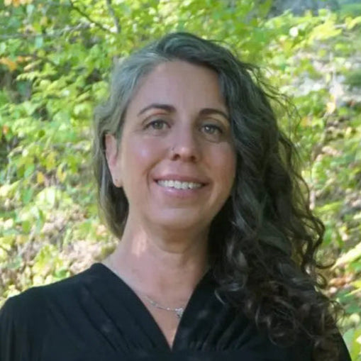 Woman standing outdoors with greenery in the background